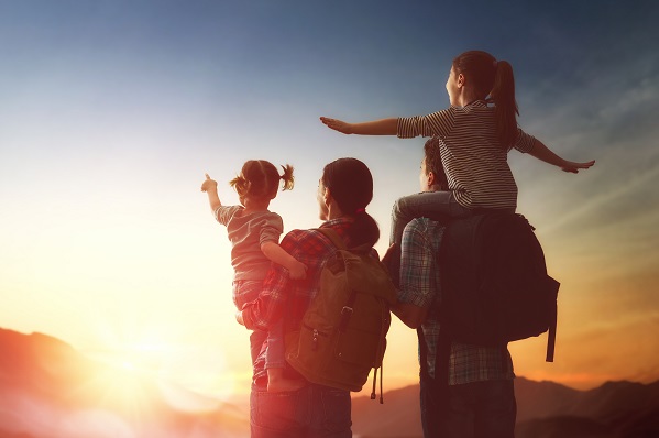 Mother, father both with rucksacks and 2 children looking at a sunrise