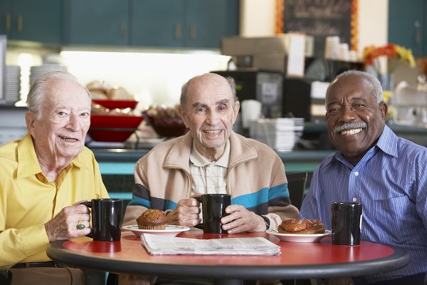 3 older men seated at a table having coffee